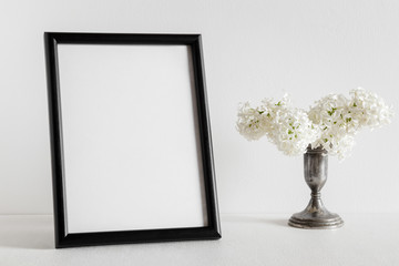 Fresh bouquet of white lilac flowers in the old, vintage vase on white background. Condolence card. Empty place for emotional, sentimental text or quote. Black photo frame.