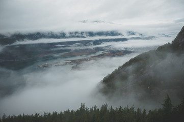 Between layers of clouds, Howe Sound appears from high above