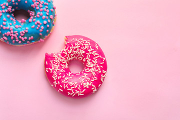 Delicious glazed doughnuts on color background, top view