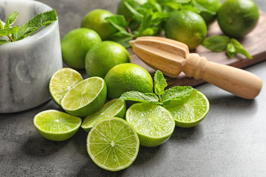Ripe limes and mint on grey background. Refreshing beverage recipe