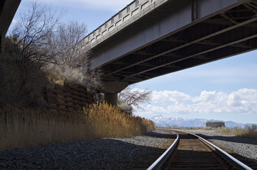 The railroad going under the highway bridge
