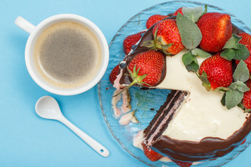 Homemade chocolate cake decorated with fresh strawberries on glass plate and cup of coffee