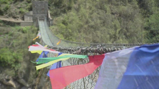 Close Up Colorful Prayer Flags blowing hang on a long metal strong bridge, route for trek at Annapurna base camp, Sign for People to good luck journey 