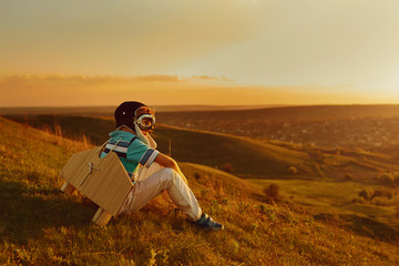A happy boy  is playing with an airplane on the nature at sunset.
