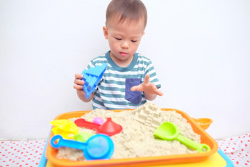 Cute little Asian 18 months / 1 year old toddler boy playing with kinetic sand at home ,Fine motor skills development, Montessori education, Creative play for kids concept