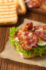 Toasted sandwich with bacon, tomato, cucumber and lettuce.