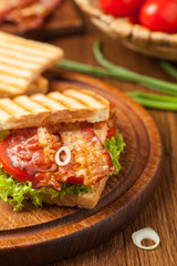 Toasted sandwich with bacon, tomato, cucumber and lettuce.