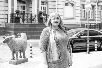 A woman of plus size, American or European appearance walks in the city enjoying life. A young lady with excess weight, xxl size at the center of the city. Natural beauty 