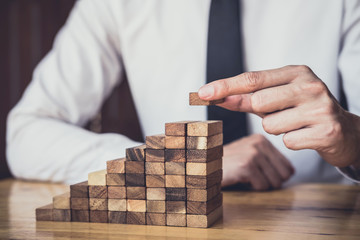 Risk To Make Business Growth Concept With Wooden Blocks, hand of man has piling up and stacking a...
