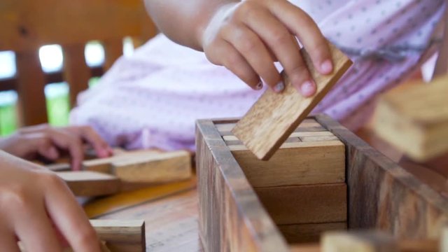Close-up of child hand while put block in to wooden box, prepare before to start game. Recorded video in 60 fps
