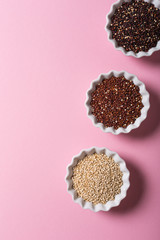 Top view of assorted Quinoa in white bowls on pink background. Flat lay with copy space. Healthy gluten free food concept.
