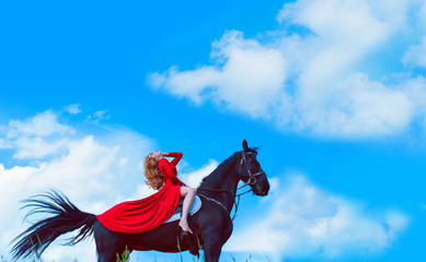Concept of freedom. Young woman in a red dress riding a horse.. Beautiful girl lifting her head up, looking into the distance 