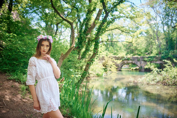 Young womqn in a white dress walking in a forest