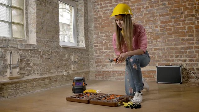 Young serious girl builder is taking tools from toolbox, building conception
