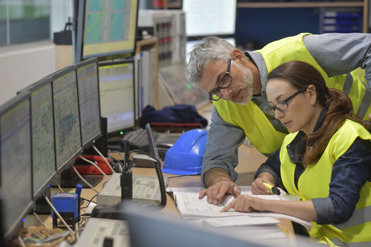 Technicians Working In Industrial Plant Control Room