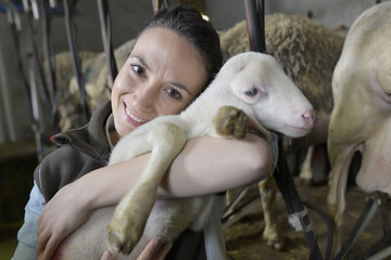 Farmer woman carrying lamb in arms