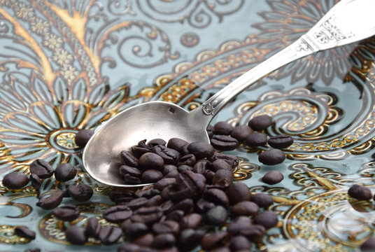Silberlöffel mit Kaffeebohnen auf einem dekorativen Tablettt