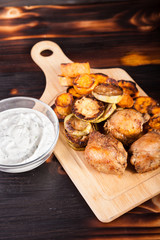 Dinner made of fried chicken and grilled vegetables and a glass bowl of sour cream souce