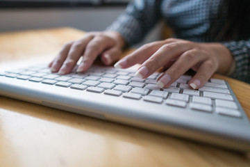 Close up hand business woman working office with computer keyboard. woman writing a blog. Female hands typing on keyboard with wood desk table