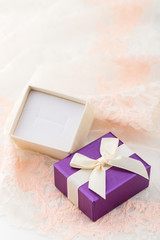 Small purple jewelry gift box with bow on lace background