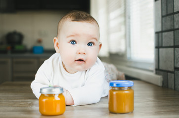 beautiful baby with blue eyes wants fruit puree pumpkin apricot Apple and peach