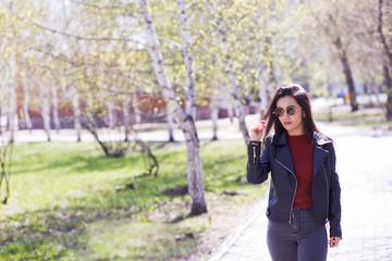 Concept of street fashion - portrait of a pretty girl. Wearing a leather jacket, round sunglasses. Spring woman. Art-bohemian rock style. Spring fashion. Stained style filters instagram