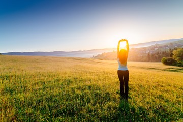 Woman enjoying beautiful sunrise at mountains.