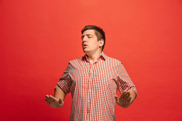 Beautiful male half-length portrait isolated on red studio backgroud. The young emotional surprised man © master1305
