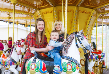 Cute little boy sitting on carousel horse