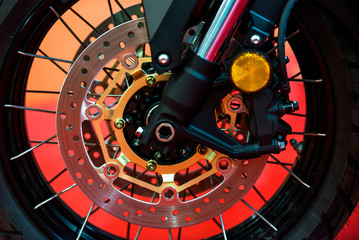 Motorcycle disk brakes and suspension on modern motorbike on orange background