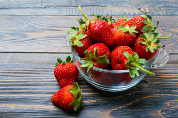 Fresh ripe strawberries in a bowl on a wooden table. Freshly harvested crop.