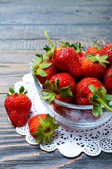 Fresh ripe strawberries in a bowl on a wooden table. Freshly harvested crop.