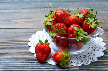 Fresh ripe strawberries in a bowl on a wooden table. Freshly harvested crop.