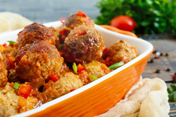 Juicy meatballs in a spicy tomato sauce on a wooden table. Dish from minced meat.