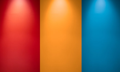 Empty red, orange or yellow and blue wall with spotlights. Illuminated lamp light. Room  interior with ceiling lamp light and colorful wall. Studio wall texture background