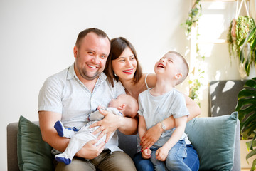 Picture of smiling parents with two young sons sitting on sofa
