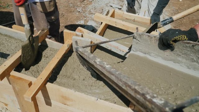 Work with concrete in the construction of a small house. Liquid concrete poured into the wooden formwork, make the base of the building