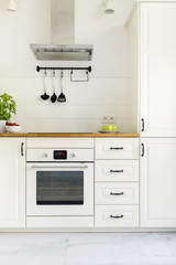 White cabinet in minimal kitchen interior with wooden countertop. Real photo