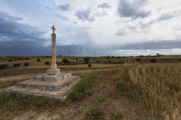 Stone cross in the middle of countryside in a stormy, cloudy and rainy evening