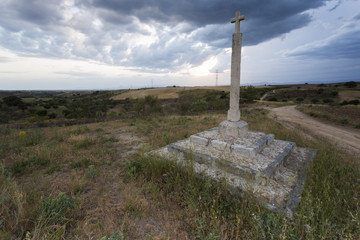 Stone cross in the middle of countryside in a stormy, cloudy and rainy evening