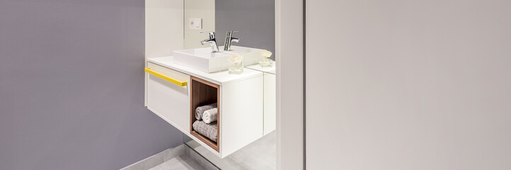Side view of modern sink with a cabinet and towels under next to an empty wall