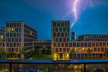 Blitzeinschlag bei einem städtischen Gewitter in München, Unwetter im Frühling über dem blauen...
