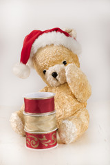 Yellow vintage Teddy Bear with rolls of Christmas silk ribbons