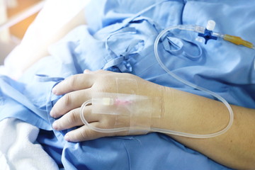 Fototapeta premium Saline solution on hand woman patient in the hospital bed.