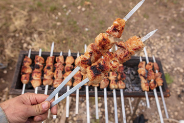 Meat roasted on sticks on charcoal in hand