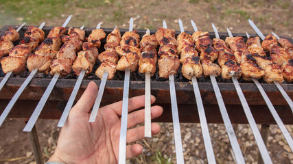 Meat roasted on sticks on charcoal in hand