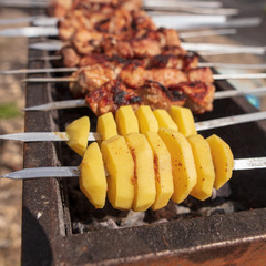 Potato on a stick is fried on charcoal