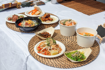 food samples, variations of diverse Asian dishes served on trays during the Asian street farmers market. Soft shell Crab Bao, roasted silkworm, Tom Yum Ramen,