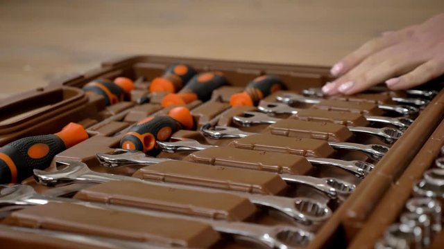 Girl builder touches tools in toolbox with her hand, repairing conception