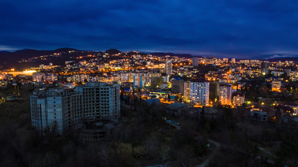 Obraz premium Drone view of the seaside with the illuminated district of the city of Sochi at dusk, Russia 
